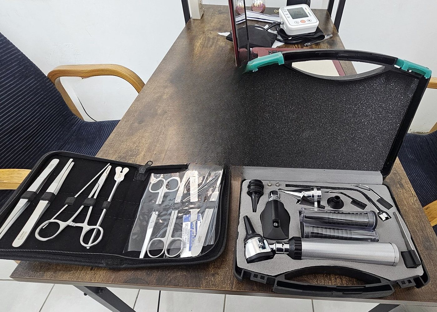 Examination and suturing instruments laid out on the desk, including an otoscope set and blood pressure monitor