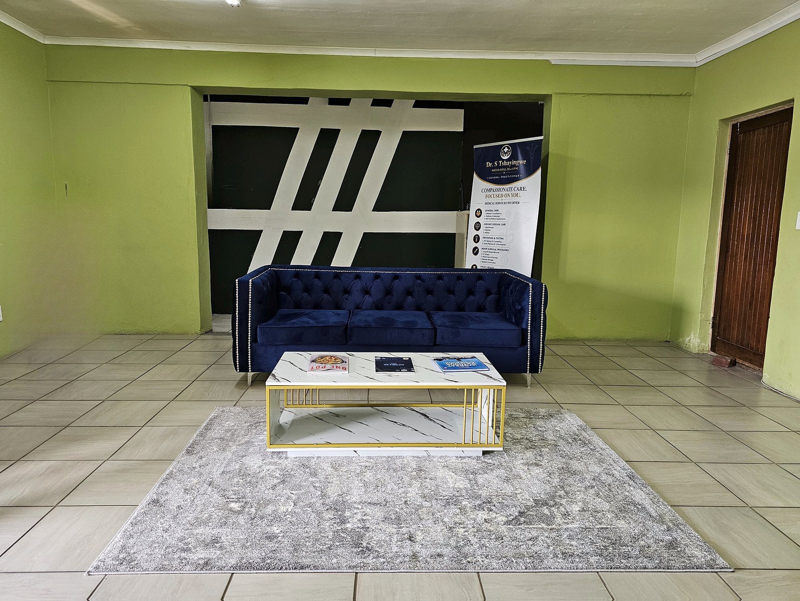 The waiting room: a navy sofa, coffee table and the practice banner against green walls